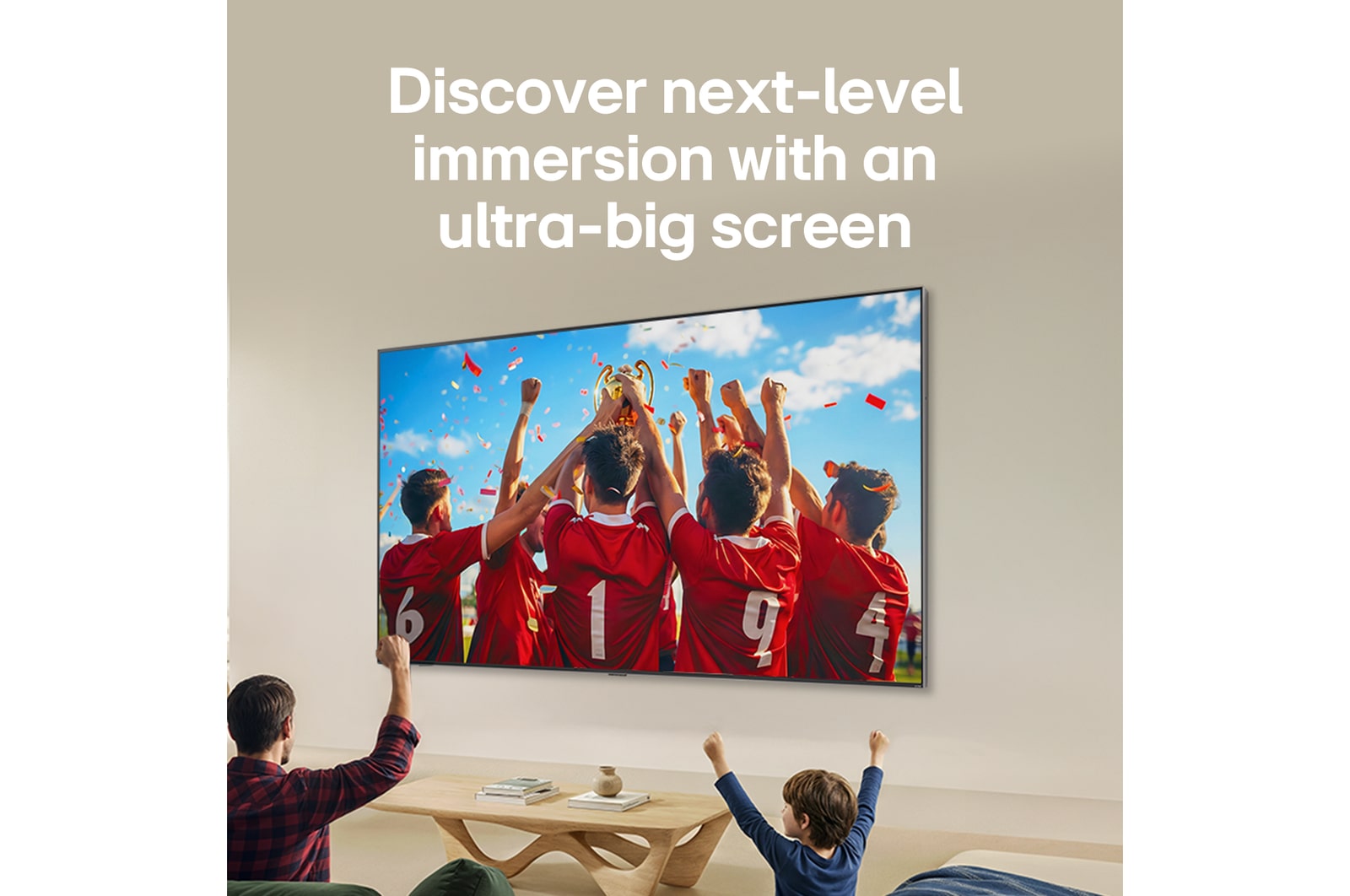 LG QNED evo AI QNED80 Mini LED Ultra Big TV is wall-mounted in a bright living room, showing a soccer celebration with vivid colors and refined picture quality across a wide screen, as a family seated on sofas cheers together.