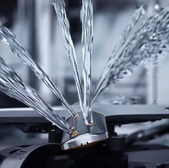 Footage of intense water streaming at different angles from rotating dishwasher blades in close-up.