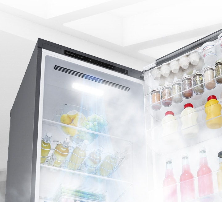 Open fridge revealing eggs, jars, juices, and fruits on shelves with LED light and mist cooling effect.