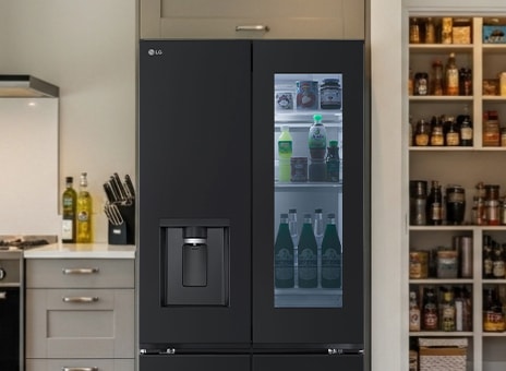 LG matte black Multi-Door fridge freezer with InstaView Door-in-Door open, showing fresh food storage. To the right, pantry shelves are filled with groceries.