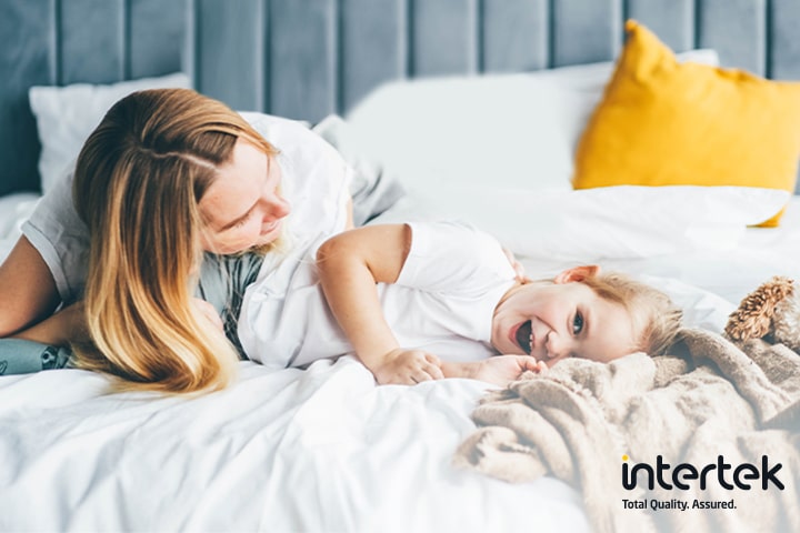 A woman and a child are lying in bed smiling