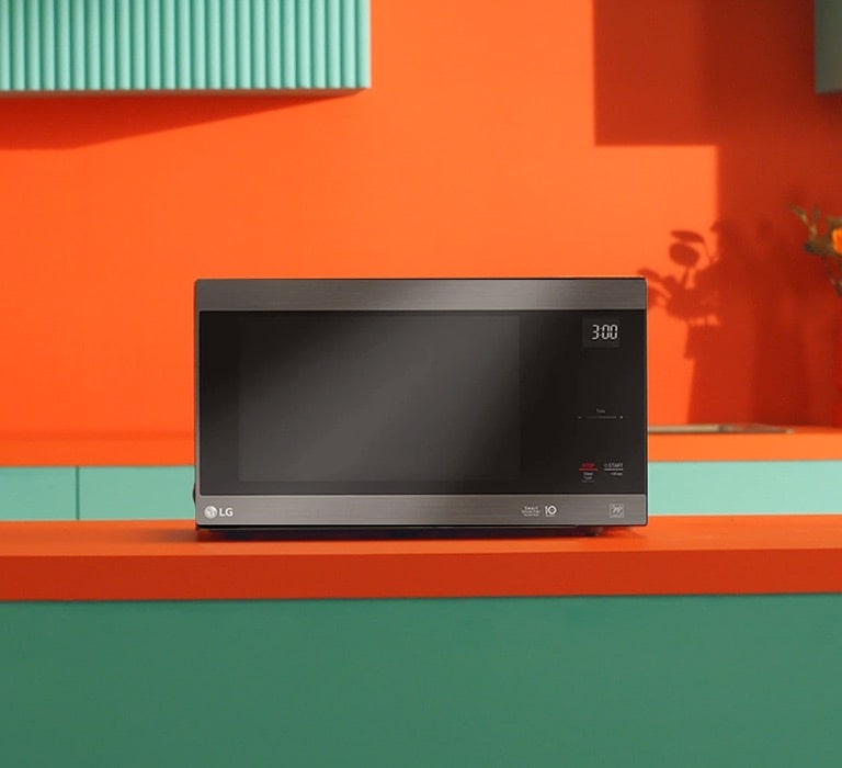 LG Neochef® microwave oven placed in bright orange and green modern design kitchen.