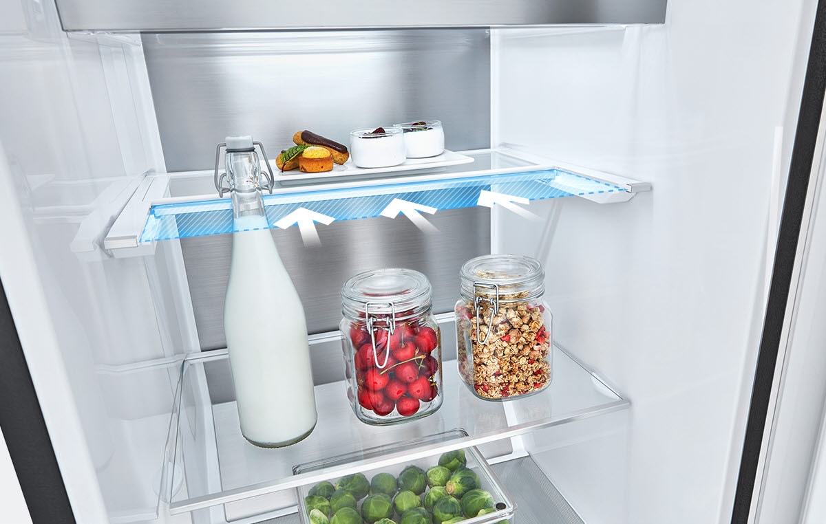 Inside a refrigerator: milk bottle, jars with cherries and granola on middle shelf, desserts and snacks on top shelf.