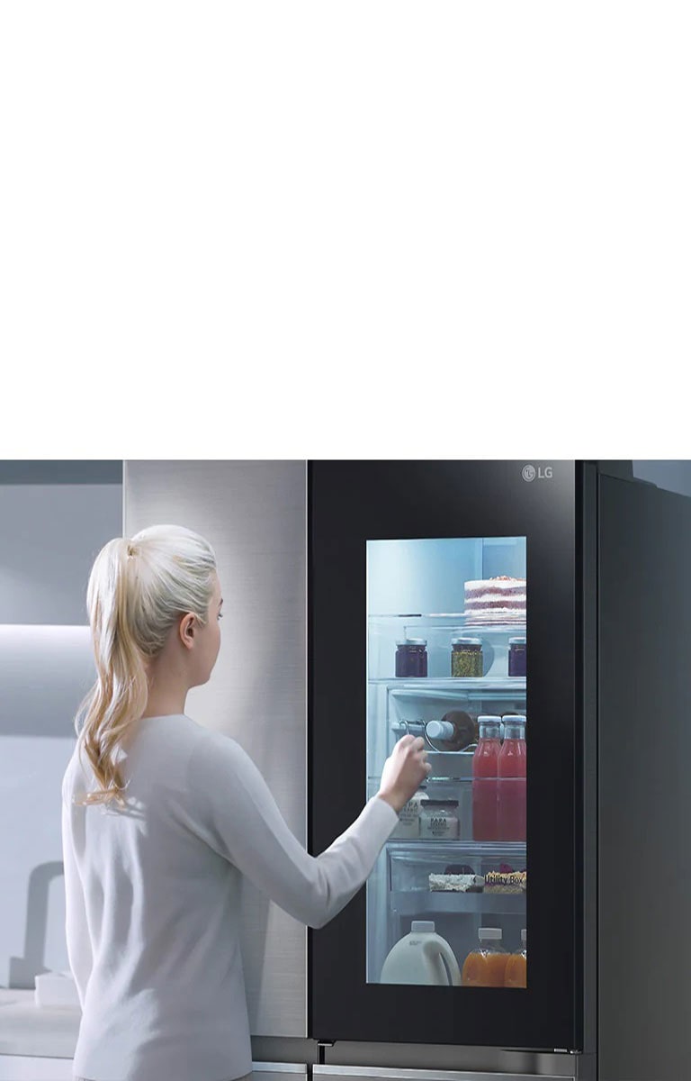 An image shows a woman at her InstaView refrigerator with knocking motion. The interior lights up and she can see the contents of her fridge without opening the door.