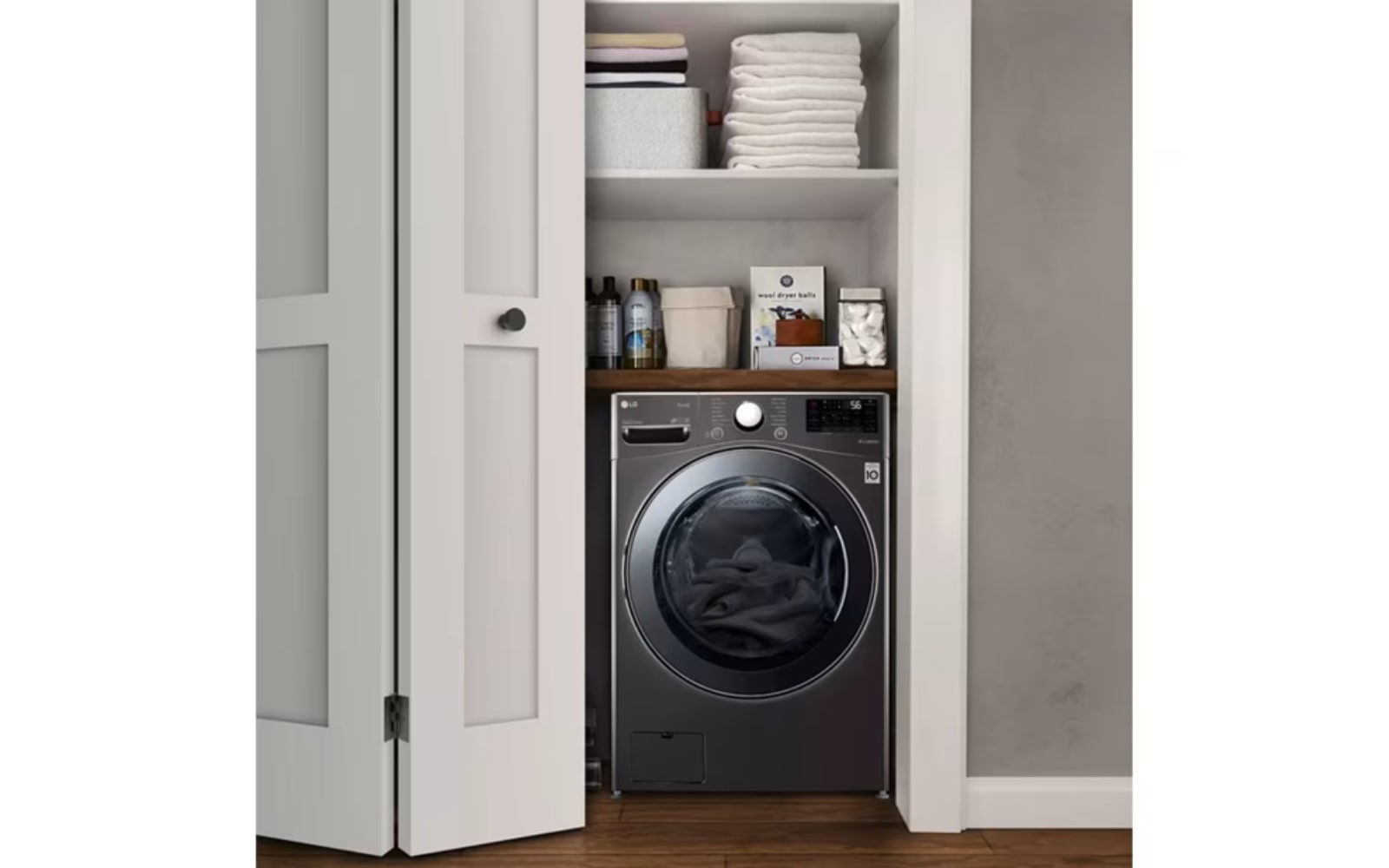 LG washing machine in a compact closet with neatly organised shelves holding towels and laundry supplies, highlighting an efficient use of space.