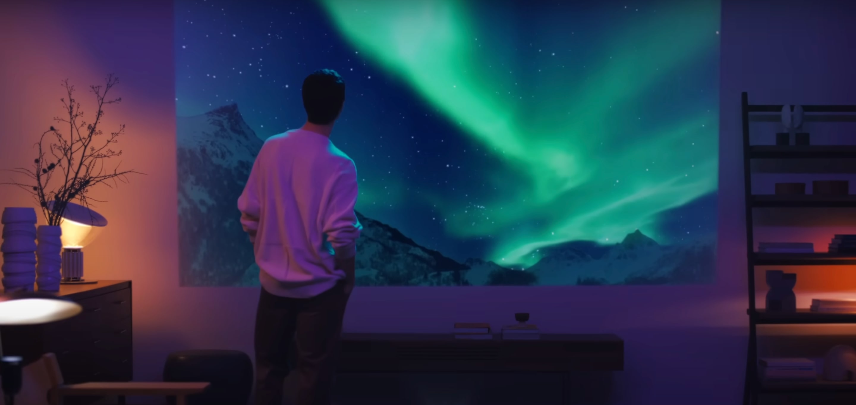 A man looks at aurora lights on a projector screen. 