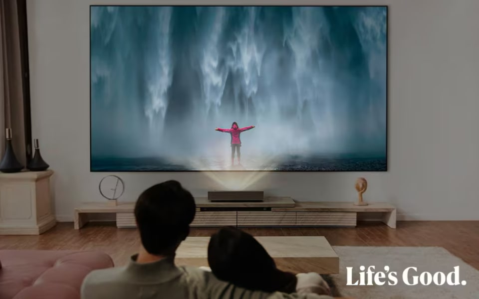 A couple enjoying a cinematic experience at home with an LG projector, displaying a vivid and lifelike image on a large screen.