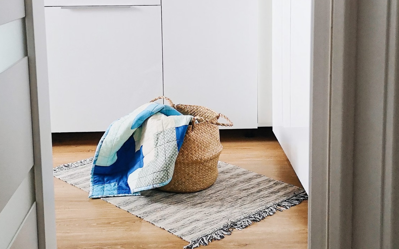 A laundry basket lies on a textured rug in a modern kitchen.