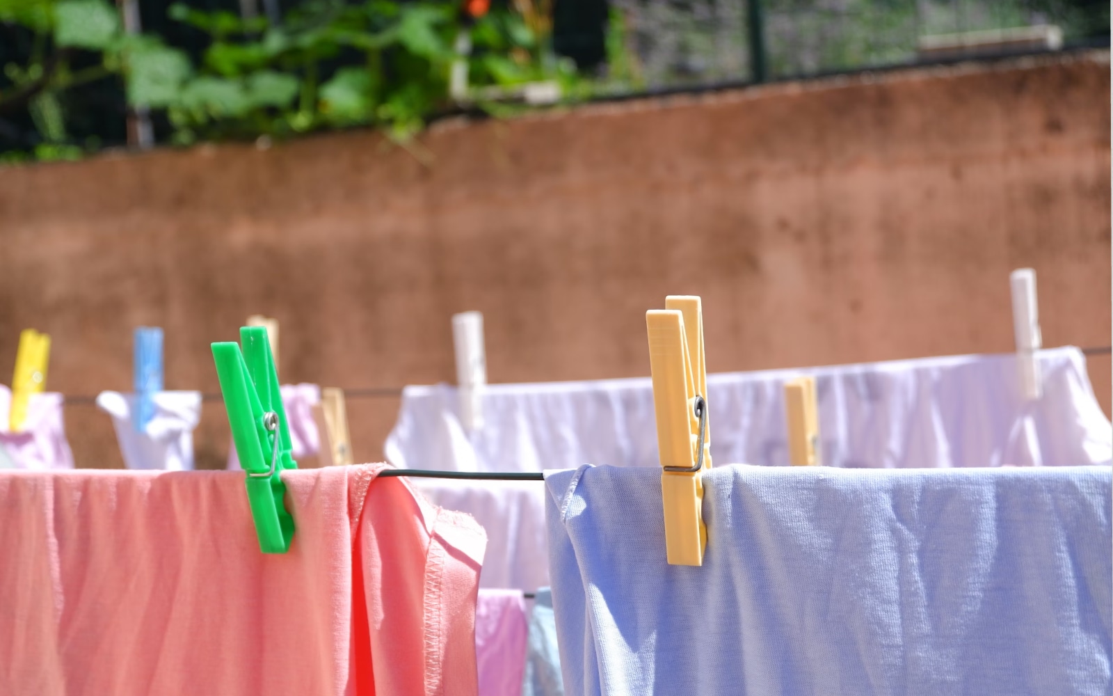  Clothes in various colours hanging on a clothesline with plastic clothespins