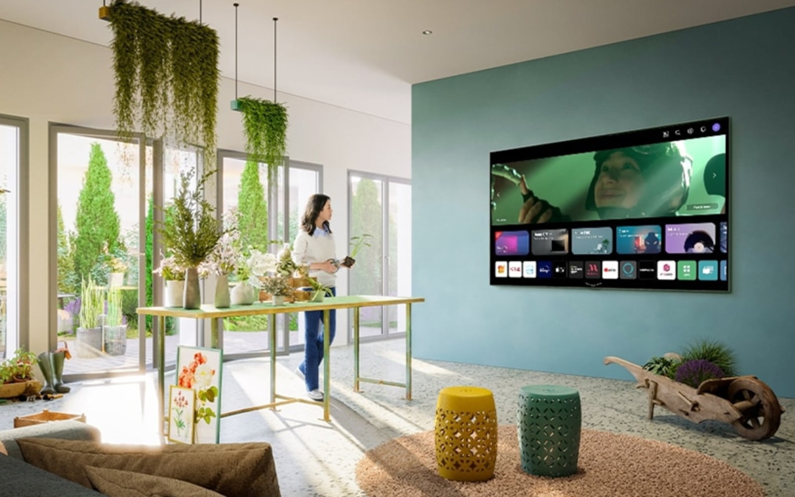 A bright, plant-filled living space with a wall-mounted LG TV showcasing the webOS home screen interface. The room blends nature with technology, creating a serene atmosphere.