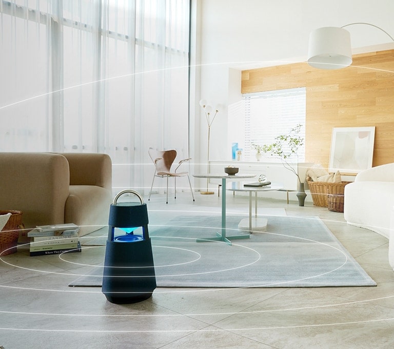 Image of sound waves spreading around XBOOM 360 lying on the floor of a minimal living room space.