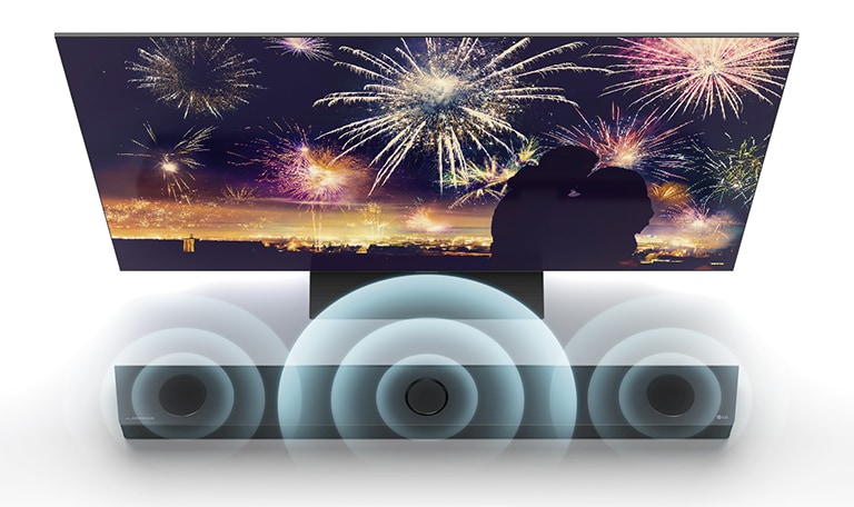 In bird's eye view, LG TV is standing on the floor and LG Sound bar is right below TV in the infinite space. On the TV screen, a silhouette of a couple on the background of fireworks. Soundwave graphics are coming from the center, left, and right speaker of the top of sound bar.