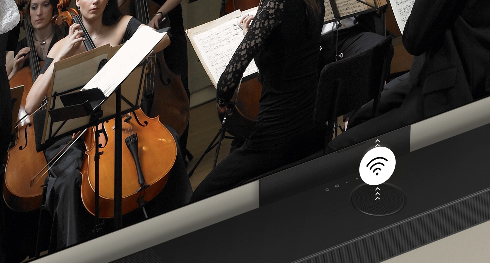 An image of an LG TV and LG Soundbar in a living room playing a musical performance. White soundwaves made up of droplets project from the soundbar, looping around the sofa and living space to depict surround sound.