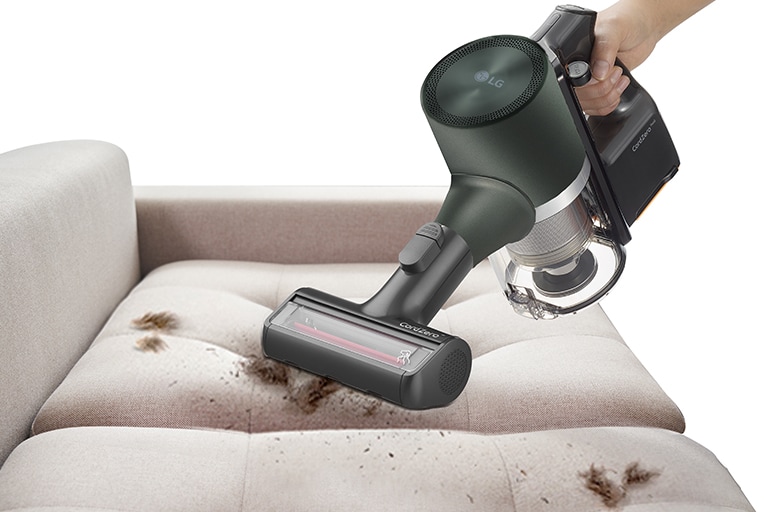 This image shows a Power Drive Mini being used to clean animal hair from a dusty sofa.
