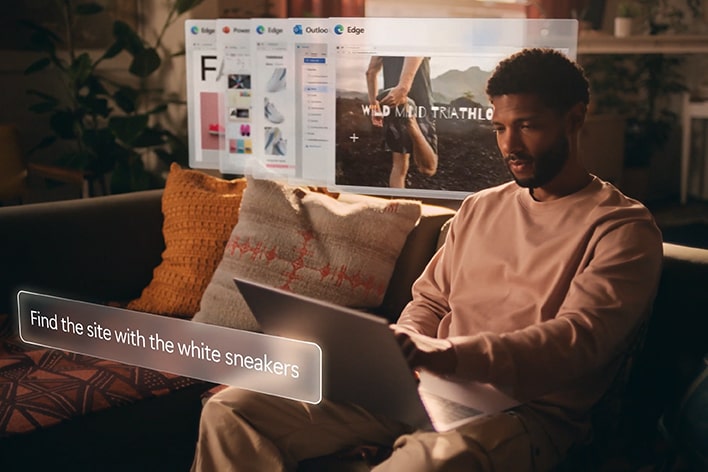 A man sitting on a couch using a laptop, with a virtual interface displaying the text 'Find the site with the white sneakers' and several browser tabs floating above the laptop screen.