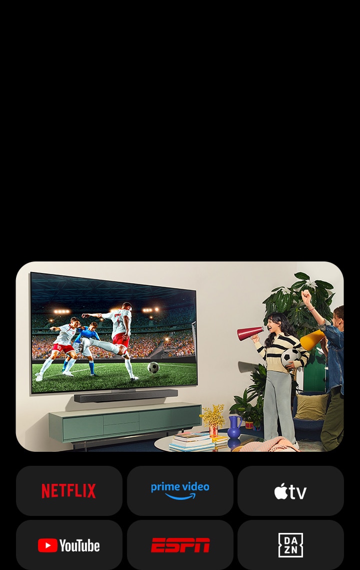 Duas mulheres assistem a um jogo de futebol em uma sala aconchegante. Uma mulher segura uma bola de futebol e ambas torcem pelo time com alto-falantes amarelos e vermelhos. Os seguintes logotipos são mostrados abaixo. Netflix, Amazon Prime Video, Apple TV, Youtube, ESPN e DAZN.
