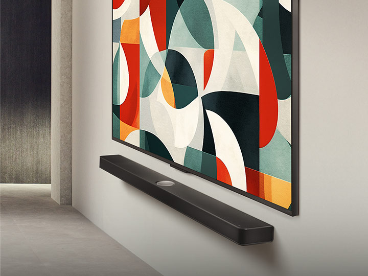 Vista ligeiramente angular da LG QNED TV montada em uma parede acima de uma LG Soundbar em uma sala de estar moderna. A LG QNED TV apresenta um fundo abstrato em verde, branco, vermelho e laranja.