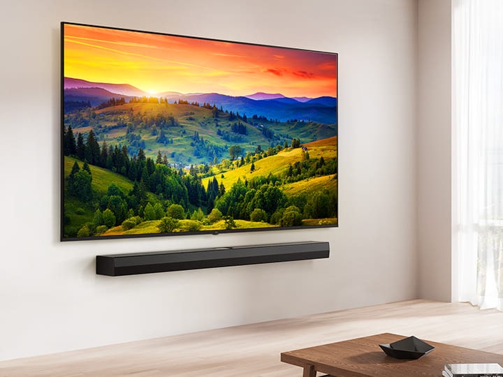 A LG UHD TV montada em uma parede acima de uma LG Soundbar em uma sala de estar moderna. A LG UHD TV exibe na tela um fundo colorido.