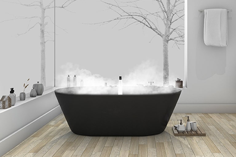 Uma banheira preta fumegante no centro de um piso de madeira com comodidades colocadas ao seu redor.