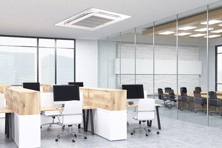 Mesas e cadeiras dispostas em um escritório enquanto uma ampla janela de vidro revela uma sala de conferências com mesa redonda e cadeiras.