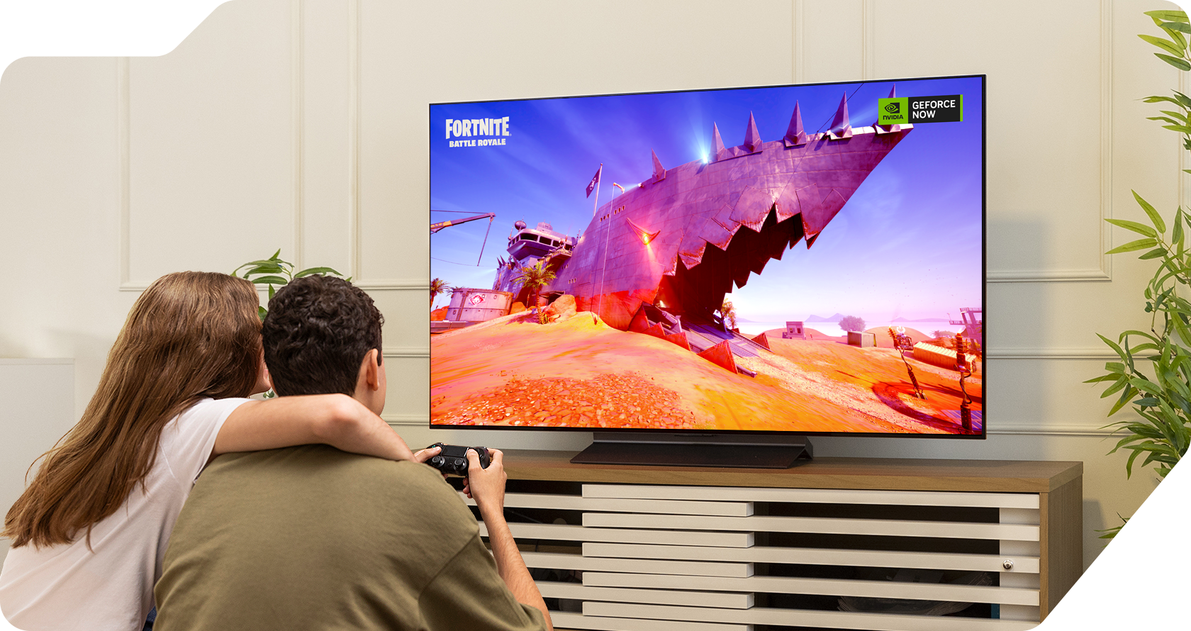 Bruno e sua namorada jogando FORTNITE na TV LG OLED C4 na sala de estar. Sua namorada coloca o braço ao redor de Bruno.