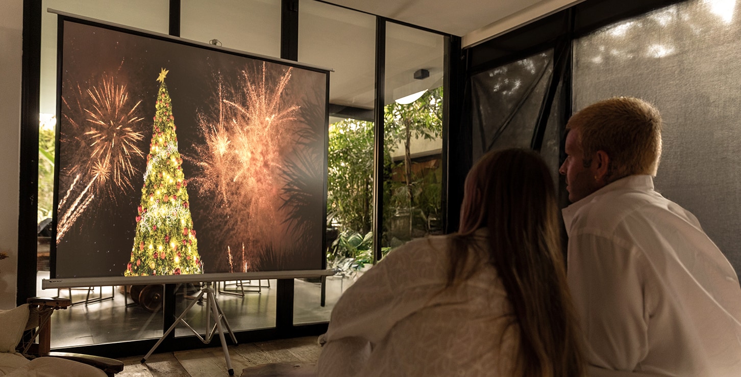 Um casal está assistindo a um vídeo em uma tela com o projetor LG CineBeam Q.