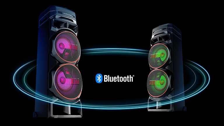 Dois RNC7s voltados um para o outro em ângulos diagonais contra um fundo preto com um logotipo Bluetooth no meio. Um tem luz roxa no woofer e o outro tem luz verde.