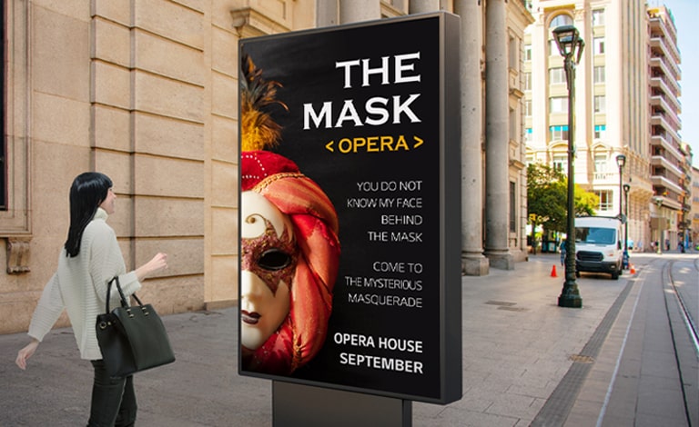 Um display com a altura de uma pessoa está instalado na rua, ao nível dos olhos, e uma mulher que passa por ele assiste ao anúncio de uma ópera com excelente qualidade de imagem na tela.