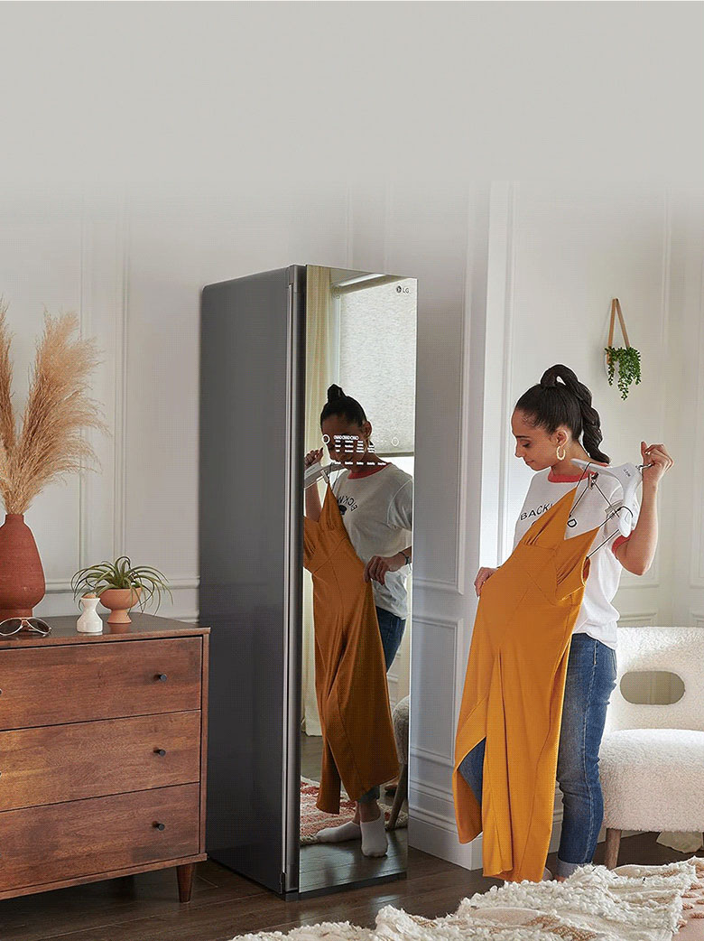 Imagem de mulher provando um vestido pelo espelho do Styler S3MFBN.