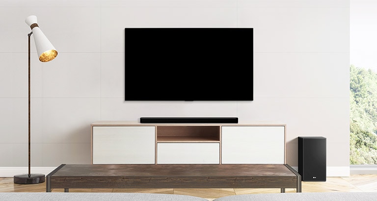 Uma TV, uma barra de som e um subwoofer localizados em uma sala de estar simples