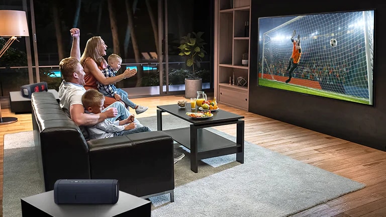 Uma família sentada no sofá assistindo ao futebol na TV