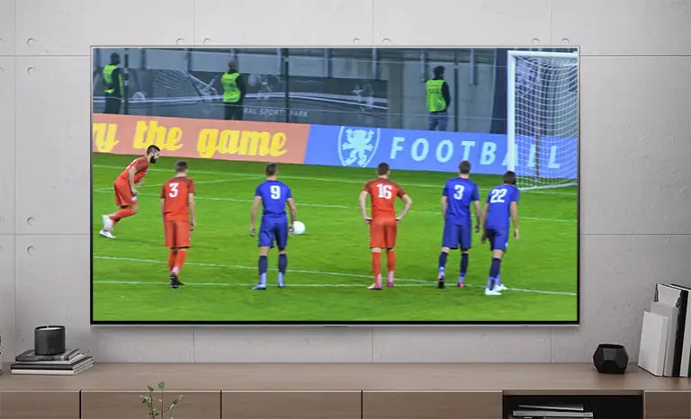Tela de TV mostrando um jogador de futebol marcando um gol de pênalti (reproduza o vídeo).