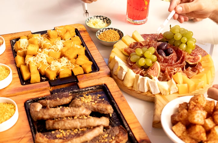 Exibição de alimentos e bebidas de festa como queijo, salame e frutas.