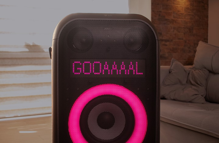 Alto-falante XBoom exibindo cor rosa na tela circular e texto dizendo 'GOOAAAAL' conforme o usuário configurou via aplicativo móvel.
