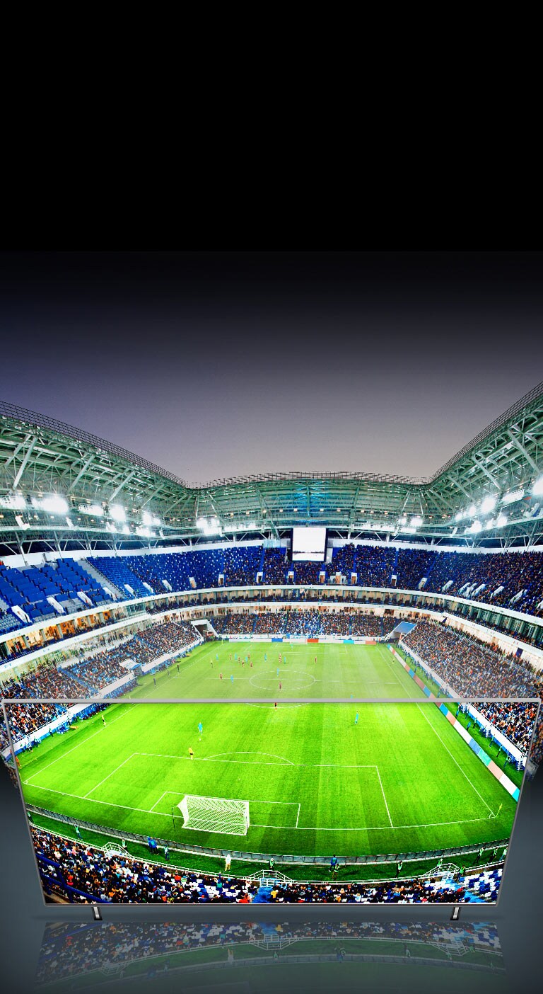 Vê-se um grande panorama de um estádio de futebol, e parte da vista é mostrada através da TV QNED.