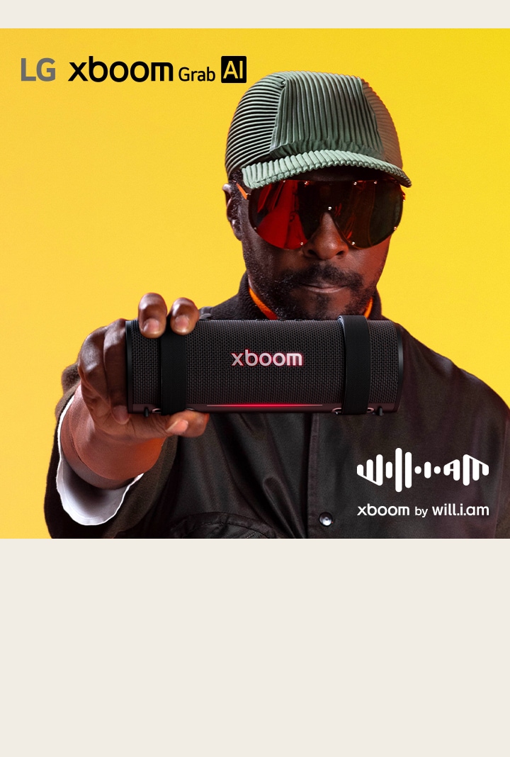 will.i.am, de roupa preta e óculos escuros, está segurando o xboom Grab na sua frente.