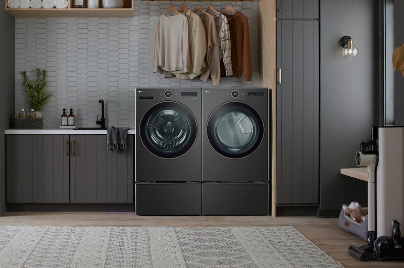 The LG Front Load Washer and Dryer set (WM6500HBA) in Black Steel, showcasing its premium aesthetic and seamless integration into a dark, modern, and stylish laundry room.