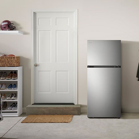 The stainless steel finish LG 28-inch 18 cu.ft. Top Freezer Refrigerator LT18S2100S, shown placed in a garage setting.