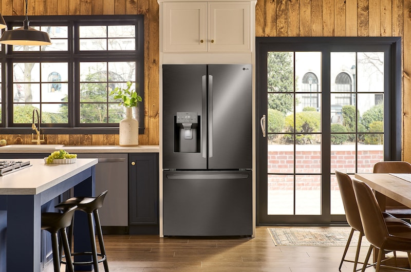 The PrintProof™ Black Stainless Steel LG 36-inch 28 cu.ft. French Door Refrigerator LRFS28XBD with water dispenser, shown installed in a warm-toned kitchen.