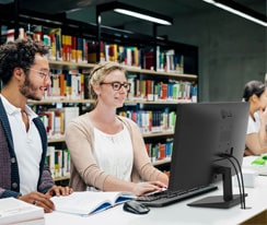 Employees sitting at office desks and having a conversation.	