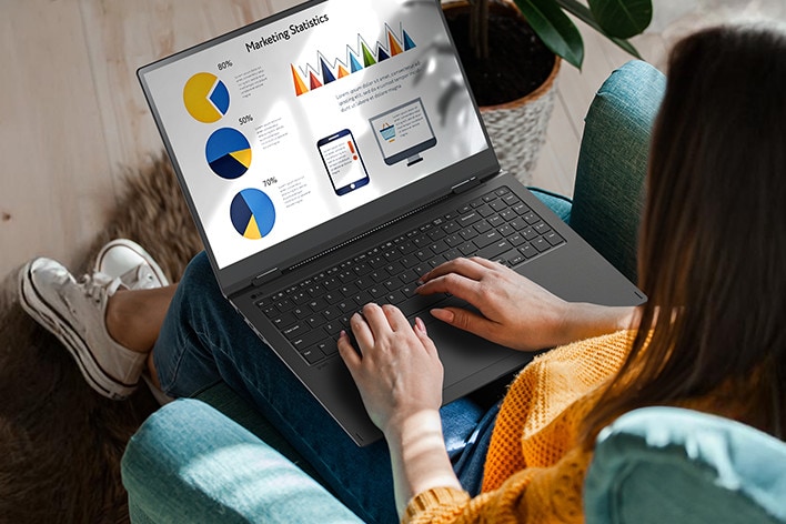 A person sitting comfortably in a chair, using a laptop that displays a presentation with charts and graphs. An animation demonstrates the anti-glare screen by showing no light reflection even when sunlight shines directly onto the display.