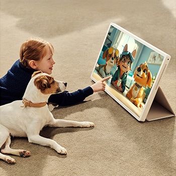 A girl with her puppy is watching a show on the LG StanbyME 2. The folio cover is used and the screen is propped up like a tablet.