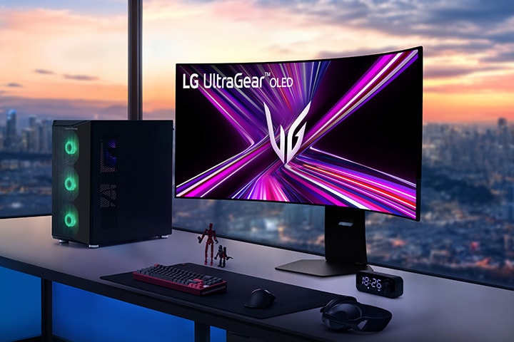 LG UltraGear OLED monitor on a gaming desk with a PC setup, overlooking a cityscape at sunset.