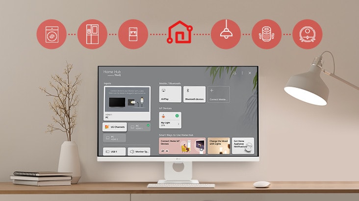 On the table's monitor screen, the Home dashboard is displayed, and at the top of the image, there are icons of household appliances such as washing machines, refrigerators, vacuum cleaners, etc., which can be controlled via the LG ThinQ app.