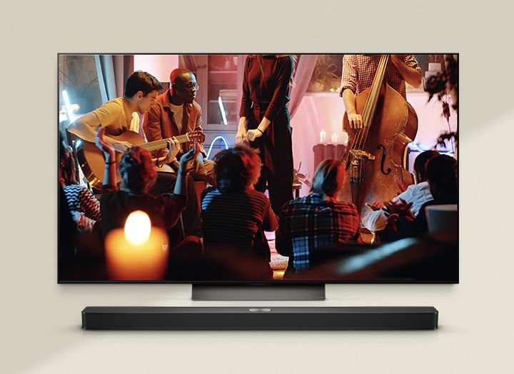 A cozy concert in a living room is playing on the screen. The WOW Interface menu appears as an overlay and the user navigates to soundbar settings