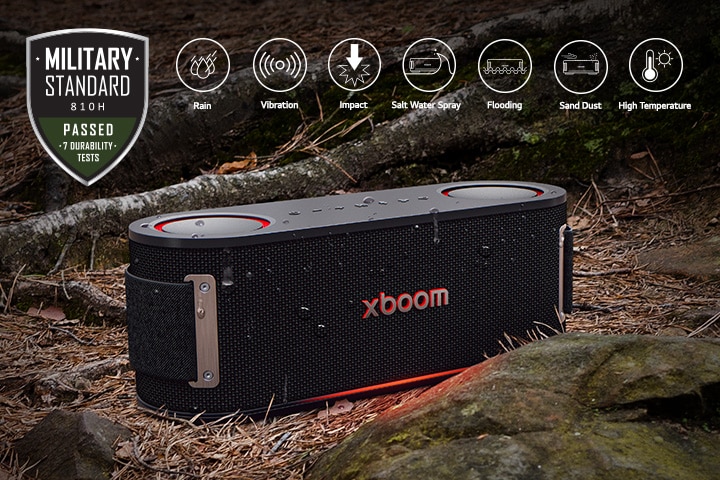 xboom Bounce is placed on soil covered with wet leaves, between a tree root and a stone. On the above left side Military standard logo is placed.