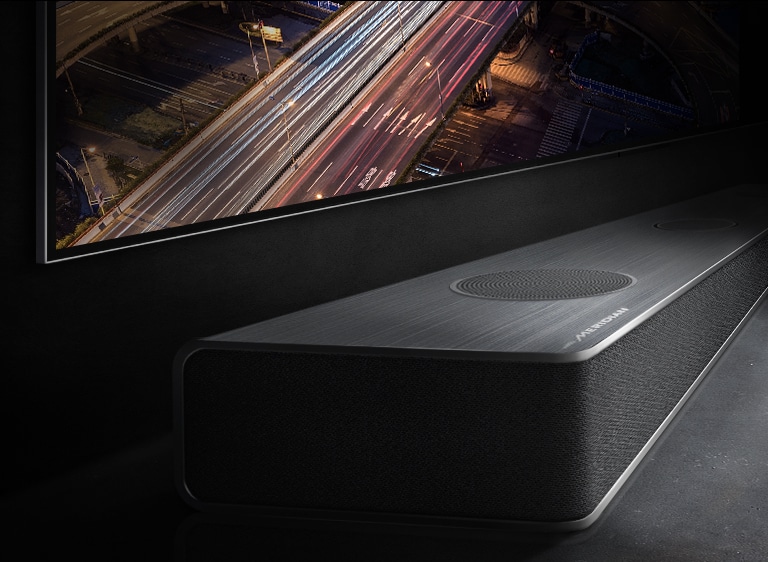 The edge of the soundbar is subtly visible below the TV screen with the night view of the road.