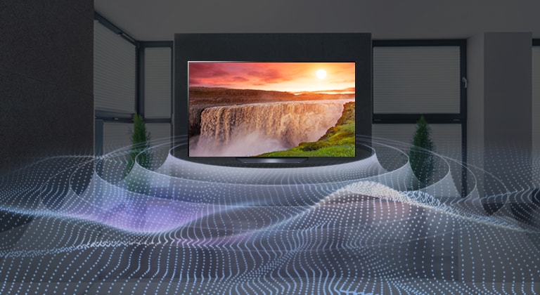 A large flatscreen TV in a dark room with a bright waterfall at sunset shown on the screen. Waves are coming from the TV in a circular pattern representing virtual surround sound.