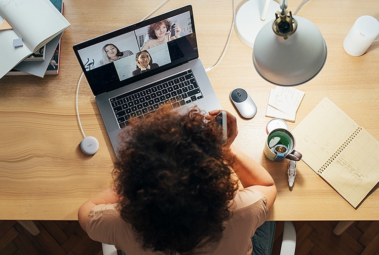 Une femme travaille sur un ordinateur et utilise la fonction de connexion sans fil pour participer à une conférence téléphonique.