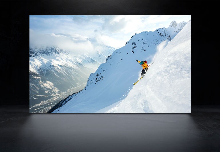 Un écran de téléviseur affiche une scène d'un homme skiant dans des montagnes enneigées à la fois sur l’OLED de LG et l’OLED evo de LG pour montrer la différence de luminosité et de netteté d'image. (lire la vidéo)